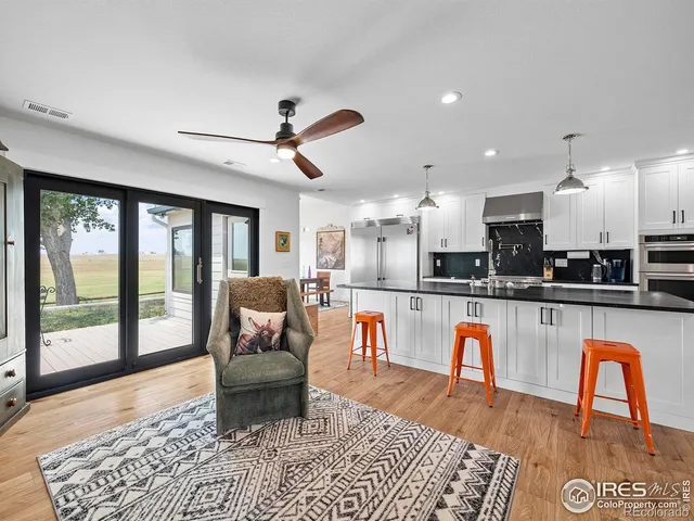 a living room with stainless steel appliances granite countertop furniture a rug a fireplace and a large window