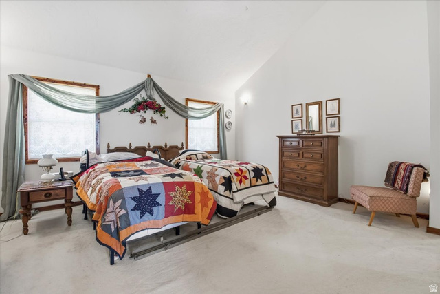 811 East Canyon Road Mayfield, UT 84643 - Photo 18 of 57 Room featuring a vaulted ceiling, two windows with wood trim, wall-mounted sconces, and light-colored carpeting