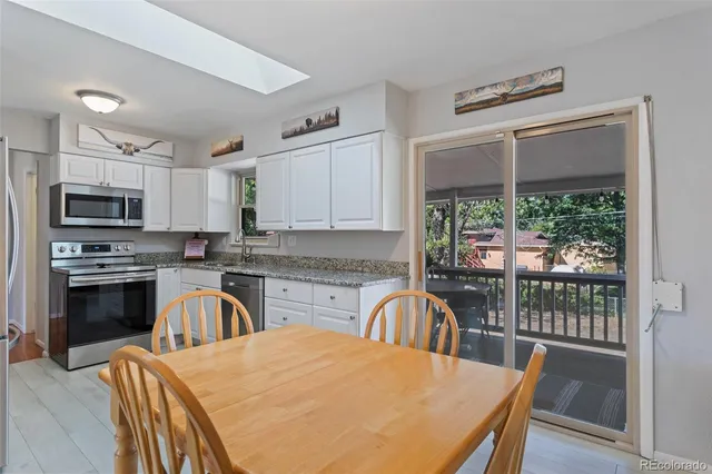 a kitchen with stainless steel appliances granite countertop a stove top oven a sink dishwasher a dining table and chairs with wooden floor