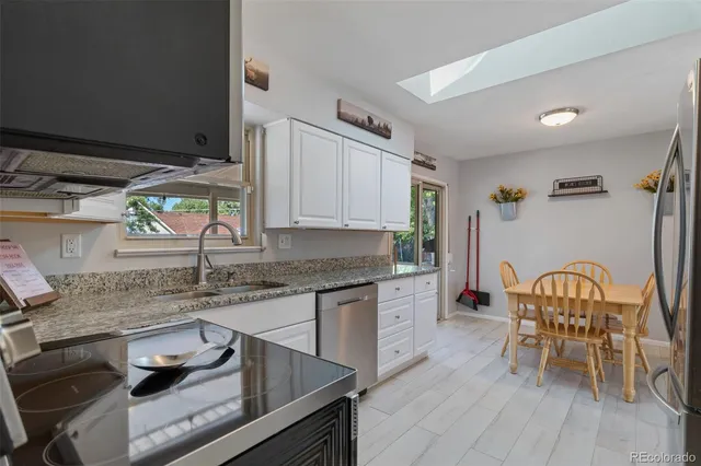 a kitchen with stainless steel appliances granite countertop a table chairs in it and wooden floors