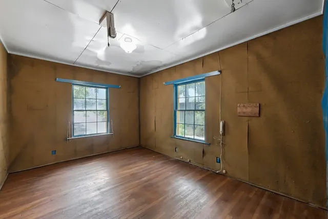 a view of an empty room with a window and wooden floor