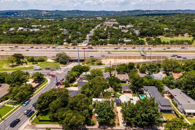 a view of a backyard with lawn chairs under an umbrella