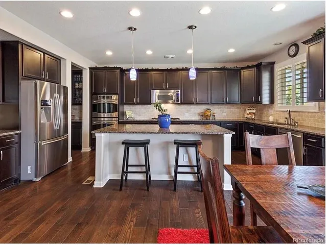 a kitchen with stainless steel appliances granite countertop a table chairs sink refrigerator and microwave