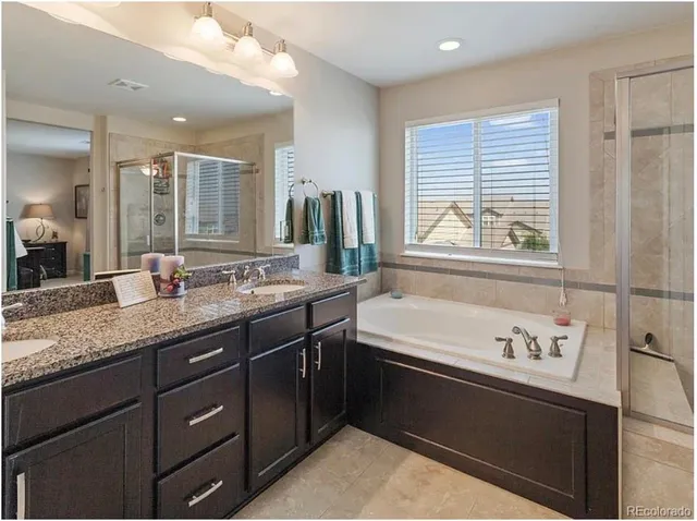 a spacious bathroom with a granite countertop sink a bathtub and mirror