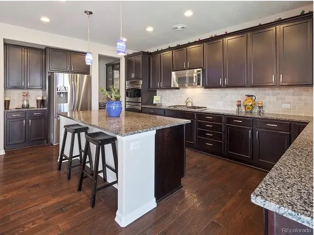 a kitchen with kitchen island granite countertop wooden cabinets and stainless steel appliances