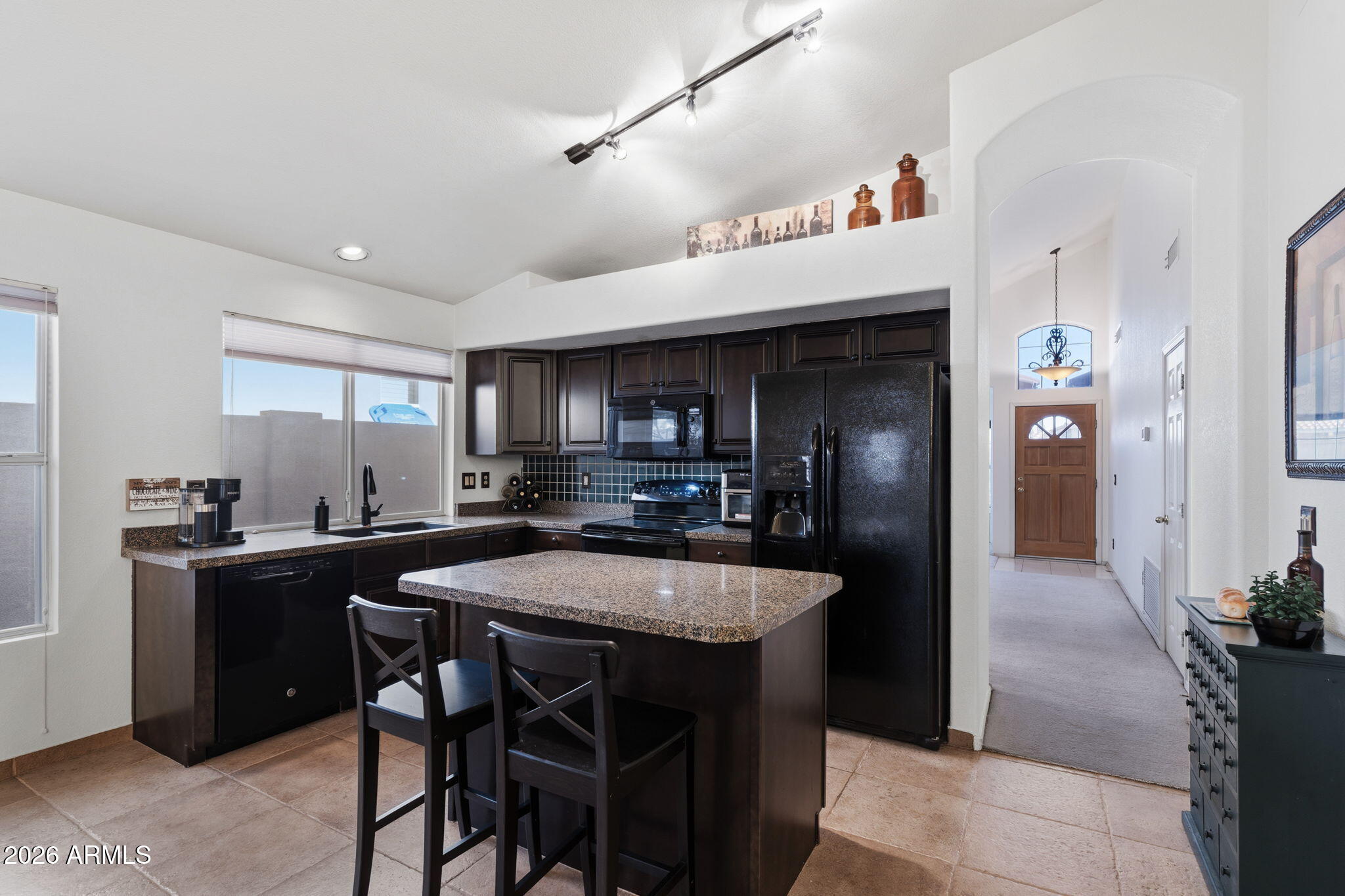 6526 East Raftriver Street Mesa, AZ 85215 - Photo 4 of 17 a kitchen with stainless steel appliances kitchen island granite countertop a table chairs sink and cabinets
