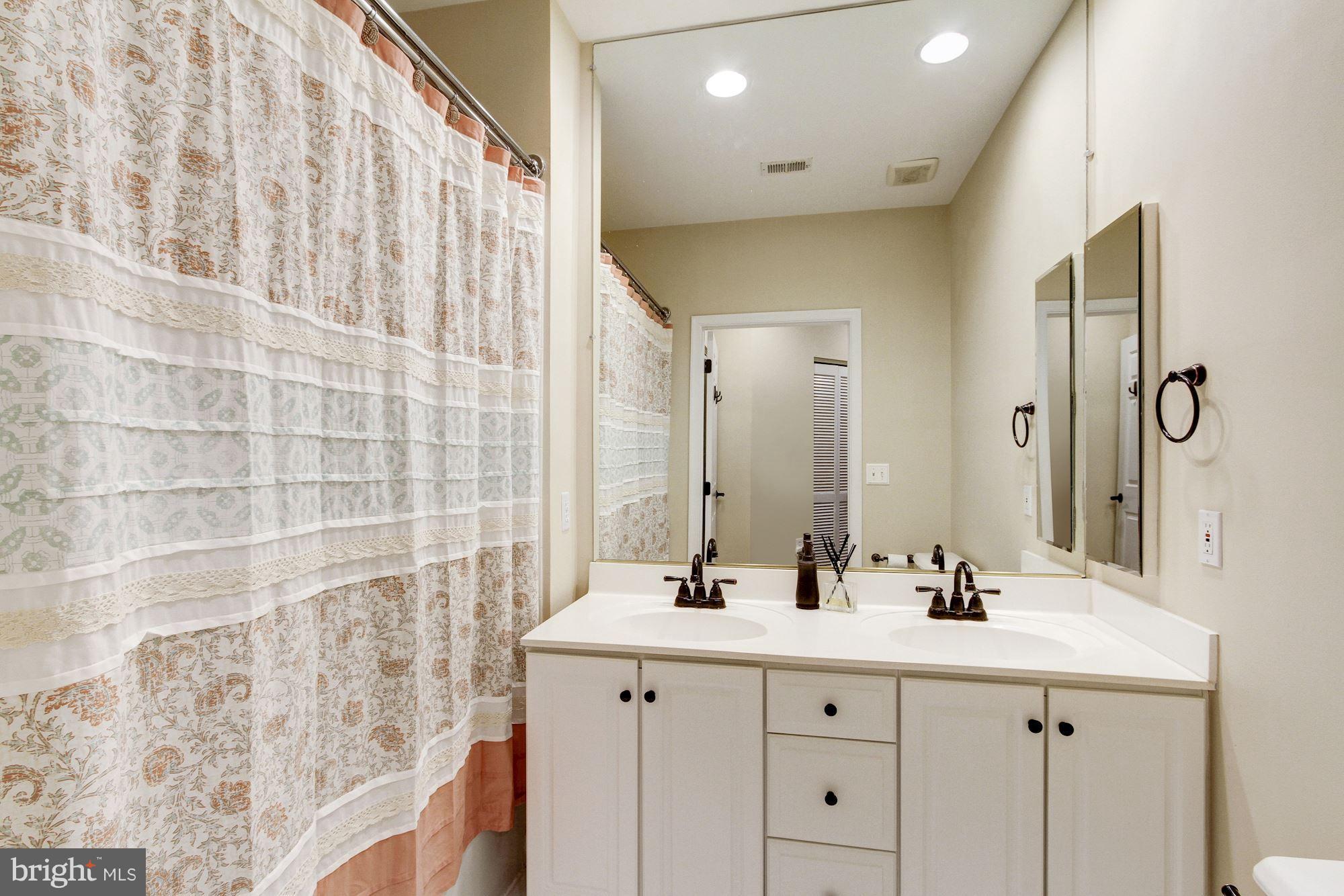 2310 14th Street North, Unit 108 Arlington, VA 22201 - Photo 17 of 22 a bathroom with a double vanity sink a mirror and a shower