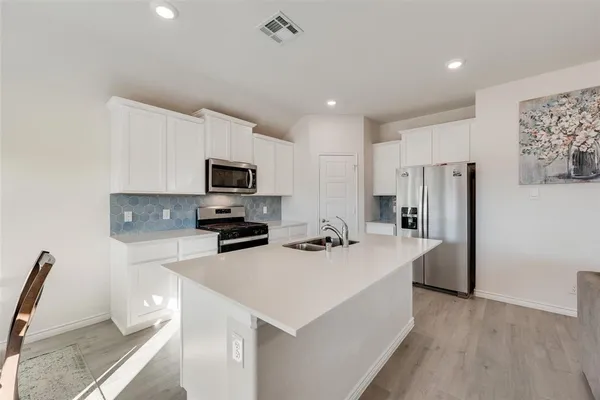 a kitchen with a sink a microwave a refrigerator and wooden floor
