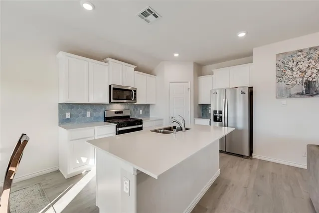 a kitchen with a sink a microwave a refrigerator and wooden floor