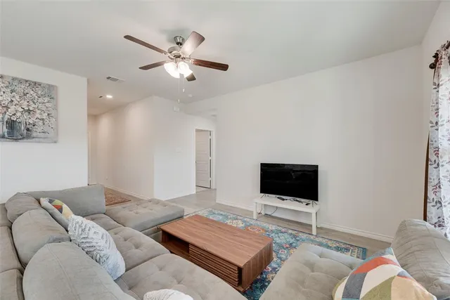 a living room with couches and kitchen view with wooden floor
