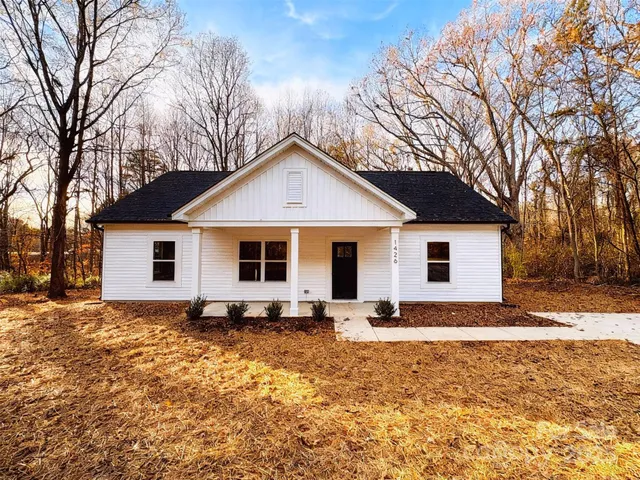 a front view of house with yard and trees in the background