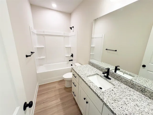 a bathroom with a granite countertop sink a toilet and shower