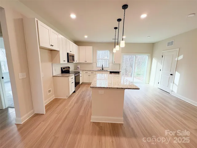 a large kitchen with cabinets wooden floor and stainless steel appliances