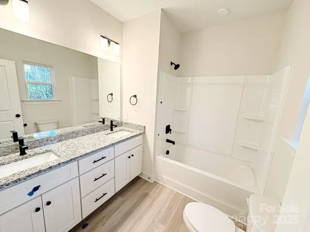 a bathroom with a granite countertop sink toilet tub and shower
