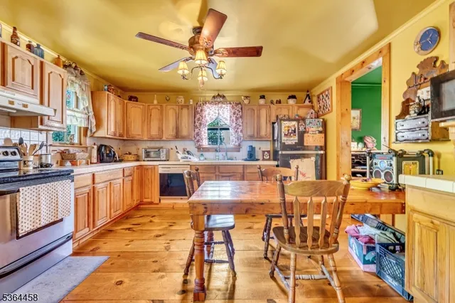 a kitchen with stainless steel appliances kitchen island granite countertop a table chairs and a view of living room