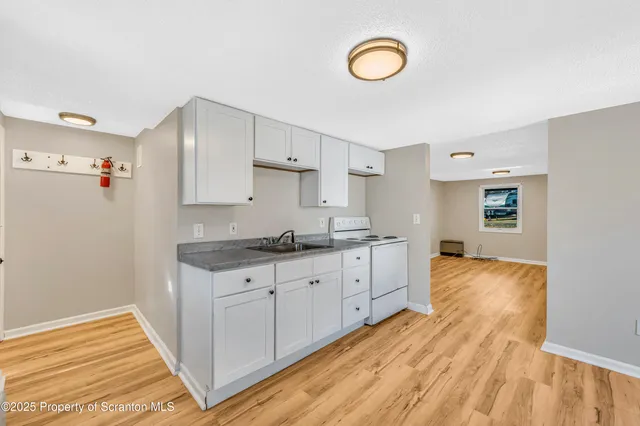 a kitchen with granite countertop a stove cabinets and wooden floor