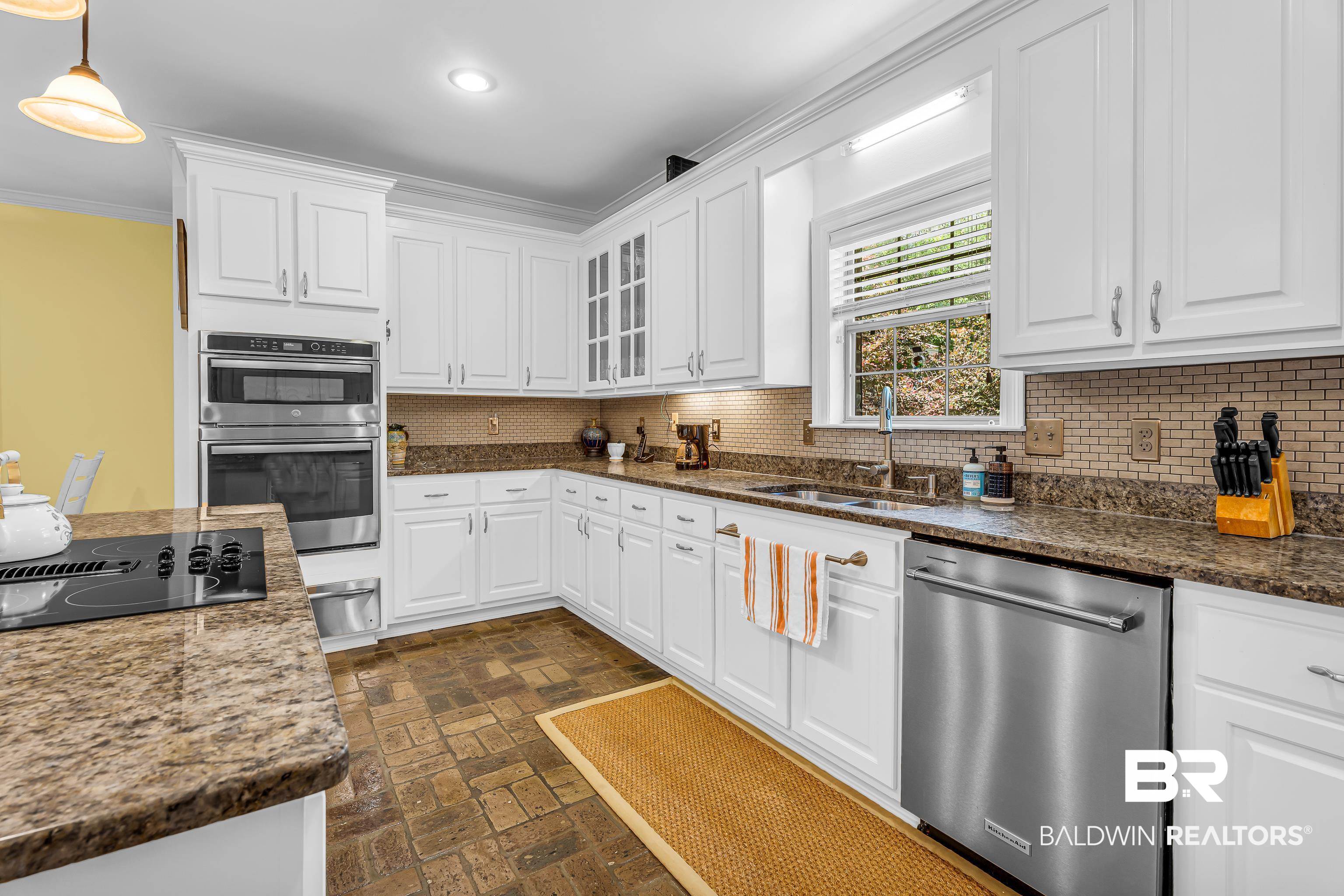 7014 Blakeley Road Daphne, AL 36527 - Photo 30 of 45 Kitchen featuring white cabinetry with brushed nickel hardware, granite countertops, and a full tile backsplash