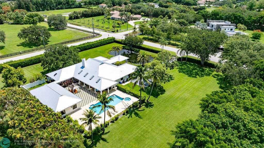 an aerial view of residential house with outdoor space and trees all around