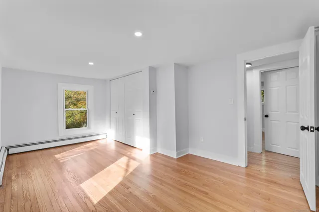 a view of empty room with wooden floor and fan