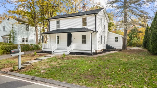 a white house that has a tree in front of it