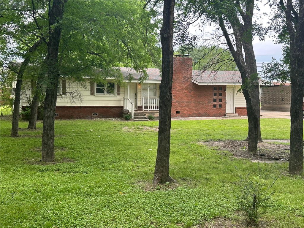 a view of a house with a yard and a large tree