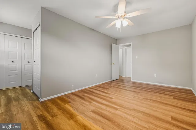 a view of empty room with wooden floor and fan