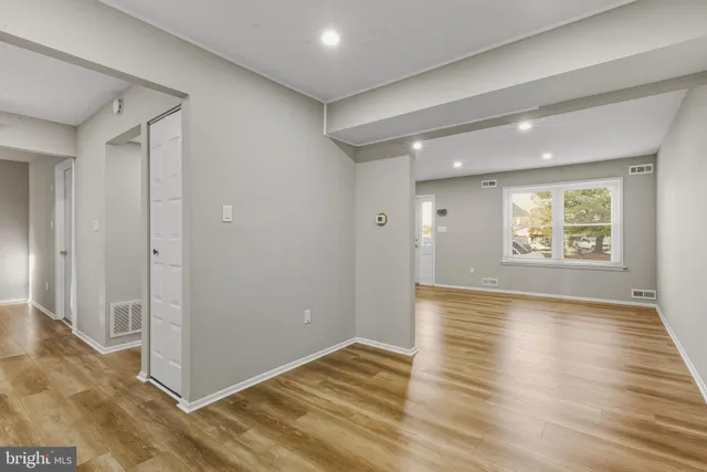 an empty room with wooden floor and windows