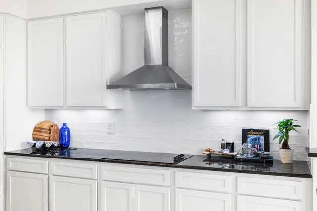 a large white kitchen with kitchen island a sink a center island and stainless steel appliances