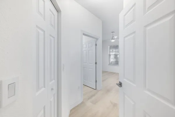 an empty room with wooden floor fan and windows