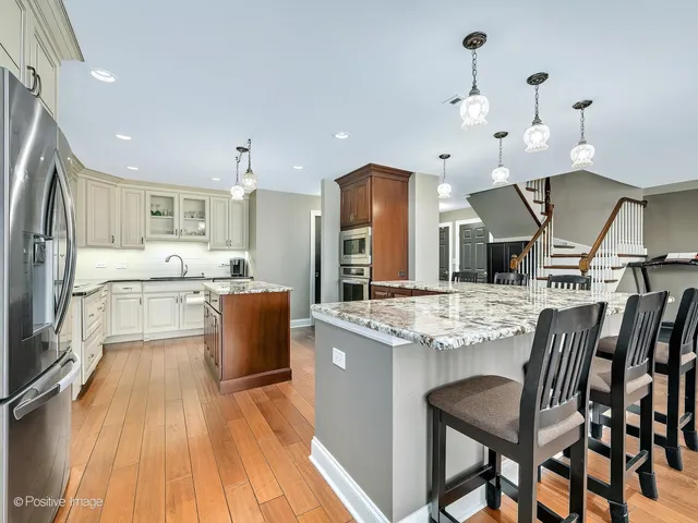 a kitchen with stainless steel appliances kitchen island granite countertop a table chairs in it and wooden floors