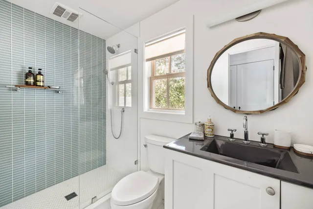 a bathroom with a granite countertop toilet sink and mirror