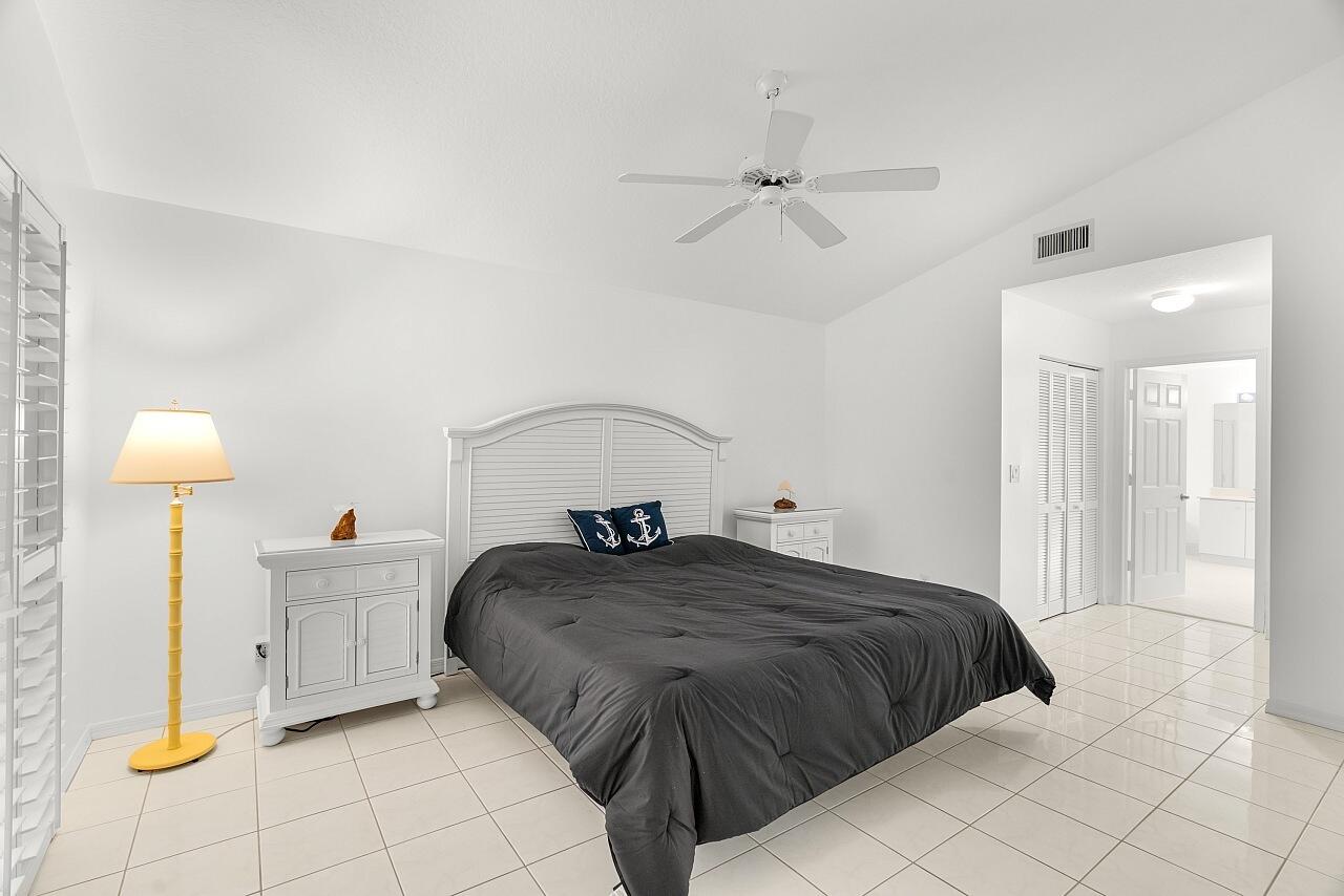 7313 Southeast Seagate Lane Stuart, FL 34997 - Photo 20 of 50 a bedroom with a bed and a lamp