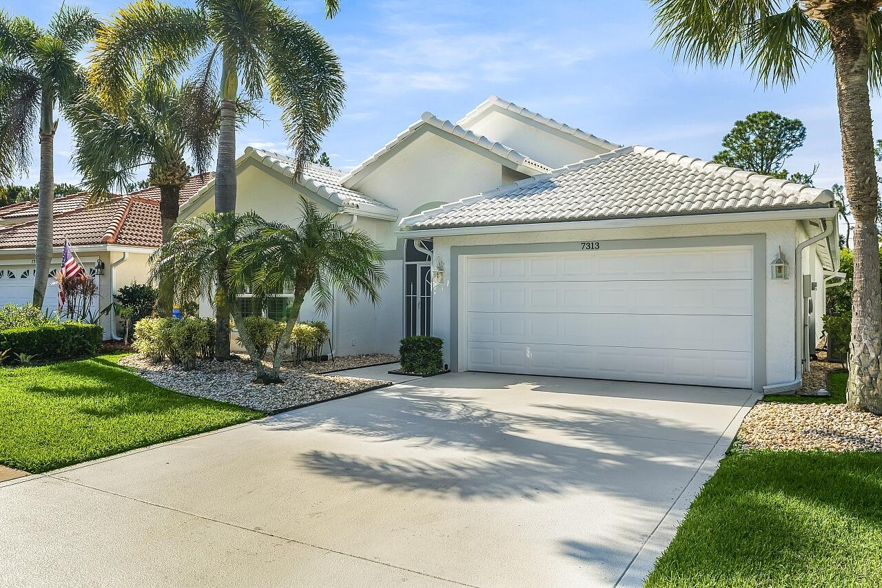 7313 Southeast Seagate Lane Stuart, FL 34997 - Photo 2 of 50 a front view of a house with a yard and garage