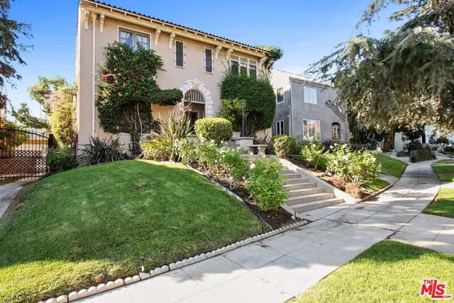 a front view of a house with a yard and potted plants