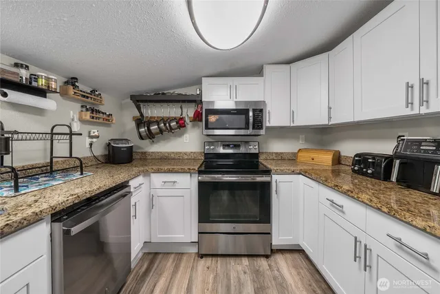 a kitchen with granite countertop a sink stove and cabinets