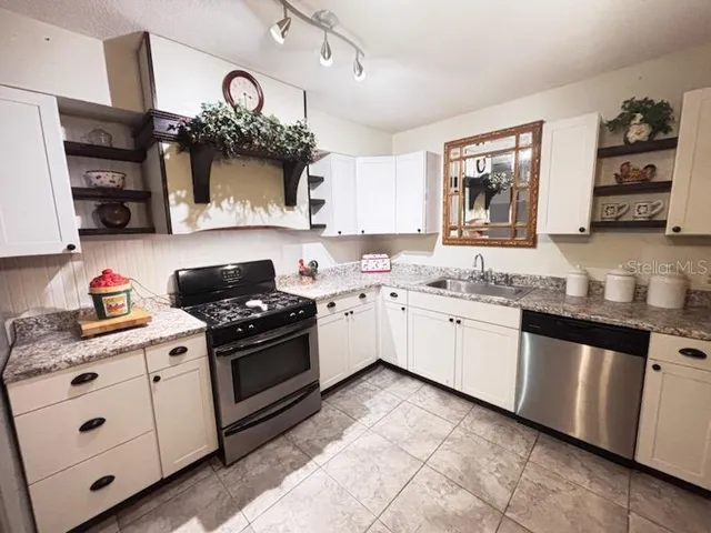 a kitchen with stainless steel appliances granite countertop a sink stove and cabinets