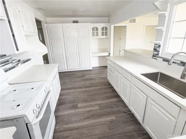 a kitchen with a sink and wooden floor