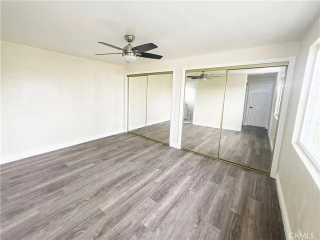 an empty room with wooden floor door and windows