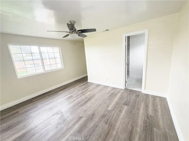 an empty room with wooden floor ceiling fan and windows