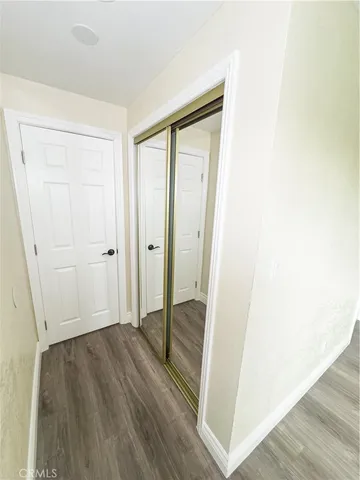 a view of a hallway with wooden floor and closet