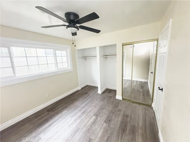 an empty room with wooden floor fan and windows