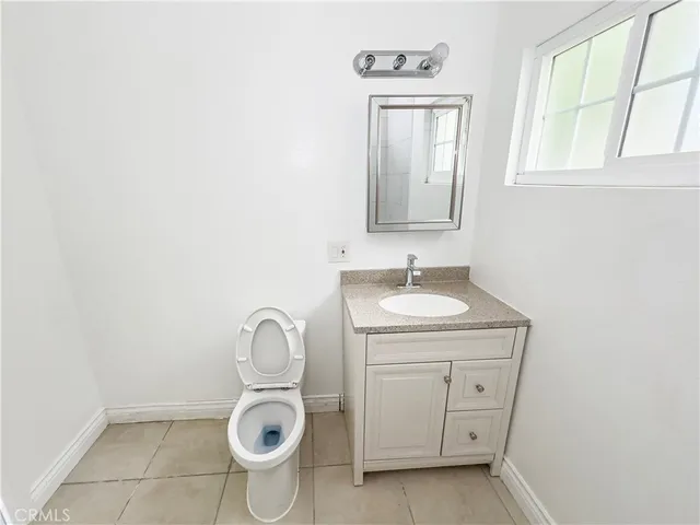 a bathroom with a granite countertop toilet a sink and a window