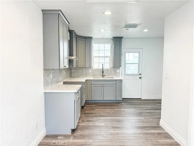 a large white kitchen with a sink and dishwasher with wooden floor