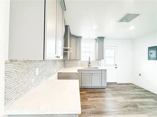 a kitchen with granite countertop a sink and white cabinets