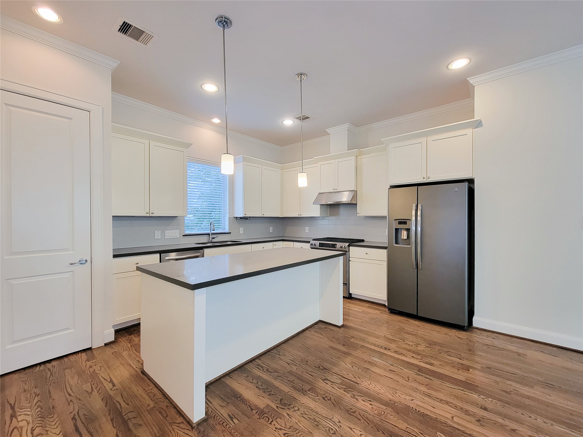 12 Hermann Park Court Houston, TX 77021 - Photo 12 of 43 a kitchen with stainless steel appliances granite countertop a refrigerator a sink dishwasher a stove and white cabinets with wooden floor