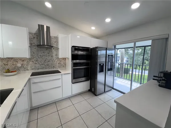 a large white kitchen with a sink stainless steel appliances and cabinets
