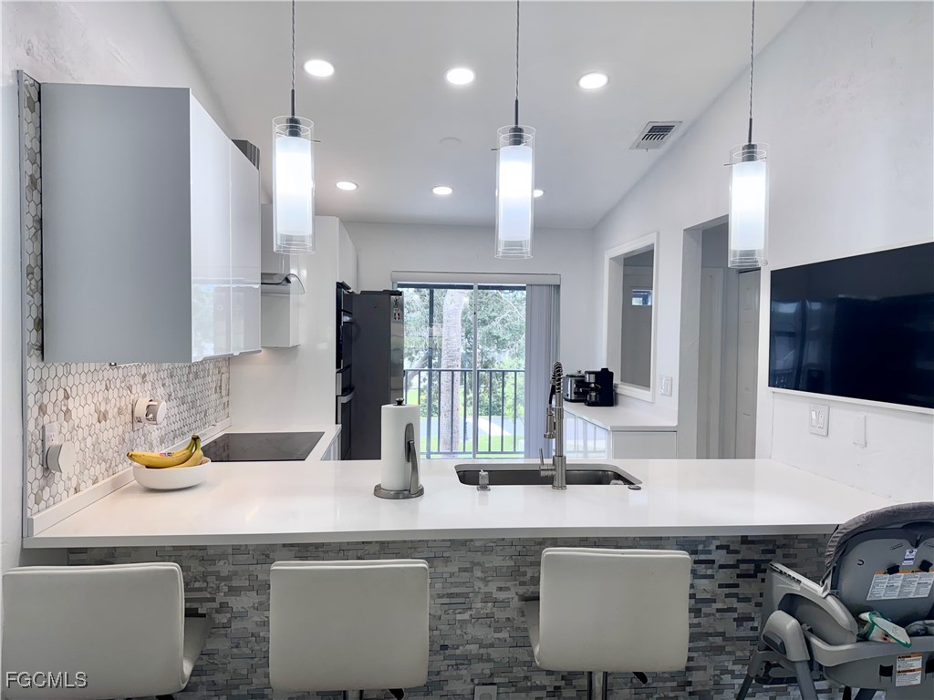 4079 Northlight Drive, Unit 1802 Naples, FL 34112 - Photo 9 of 29 a kitchen with kitchen island granite countertop a sink a counter top space and living room view