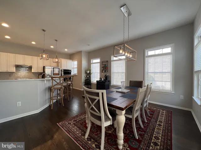 a kitchen with a sink dishwasher a stove and a dining table with wooden floor