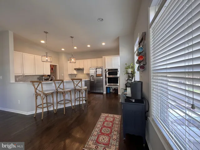 a kitchen with stainless steel appliances granite countertop wooden cabinets a sink a stove a refrigerator and dishwasher with wooden floor