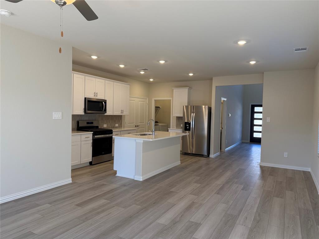 1736 Arches Road Anna, TX 75409 - Photo 4 of 18 Kitchen featuring stainless steel appliances, white cabinetry, a center island with sink, light wood-style flooring, and ceiling fan